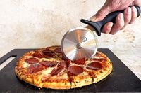 A hand using a Mercer pizza cutter to slice a pepperoni pizza