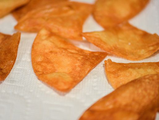 Fried chips are drained on a paper towel.