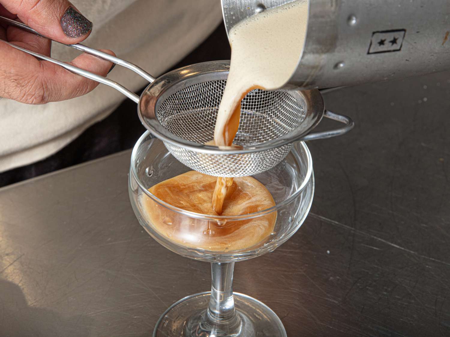 Espresso martini preparation pouring through a strainer into a glass