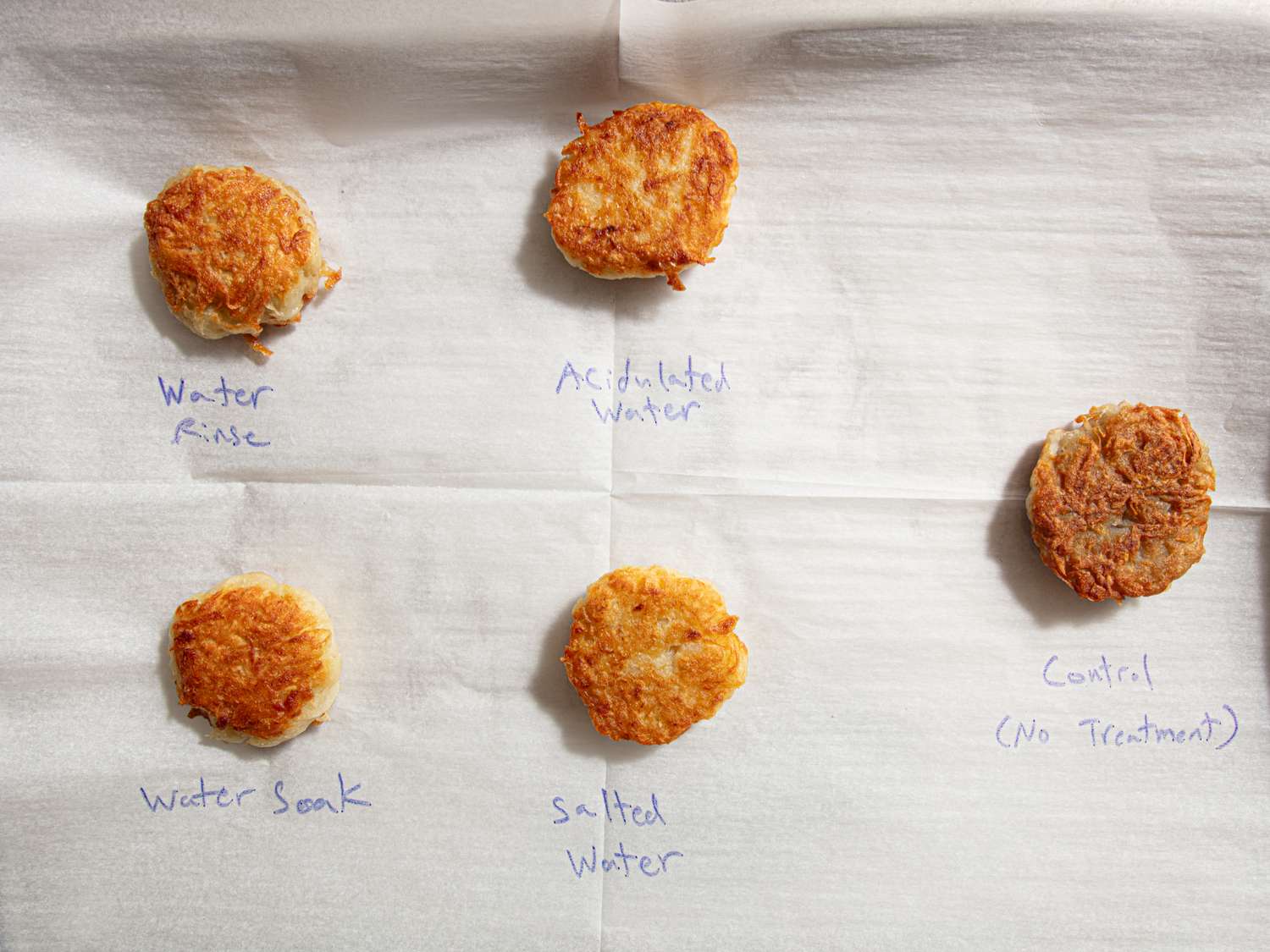 Five potato samples labeled with different treatments including rinses and soaking displayed on parchment paper for comparison testing