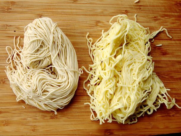 An overhead of thin, straight ramen noodles next to thicker, wavy ramen noodles.