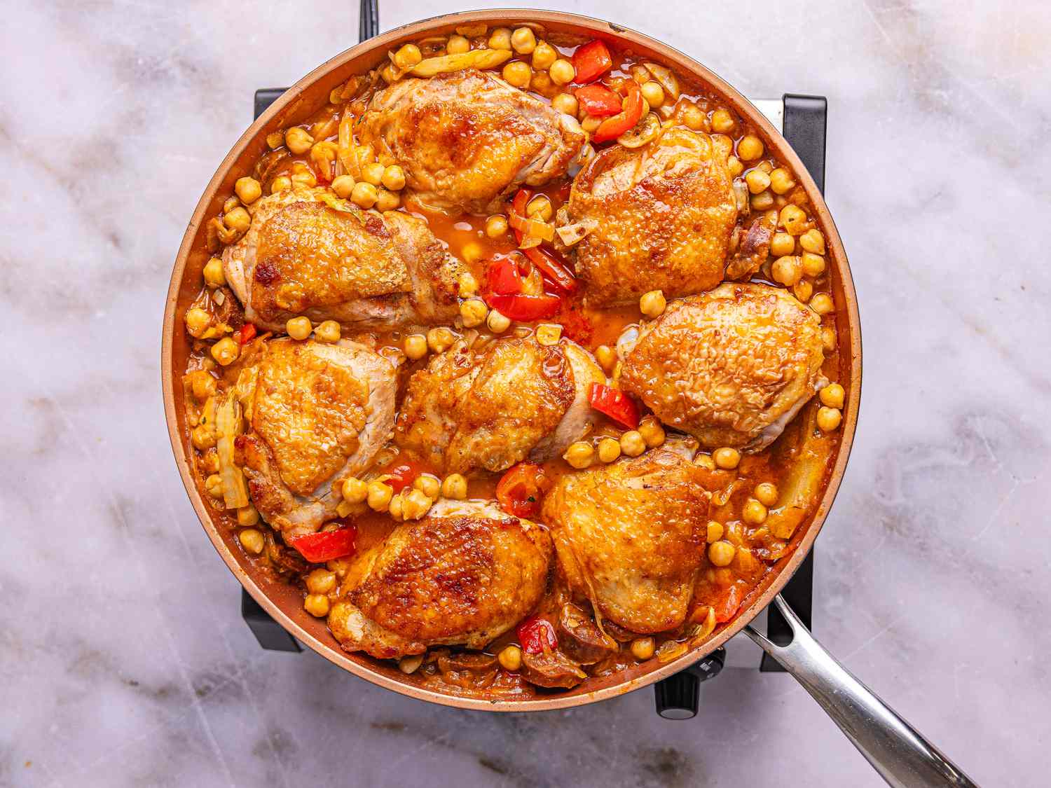 Braised chicken thighs with chickpeas and vegetables in a skillet