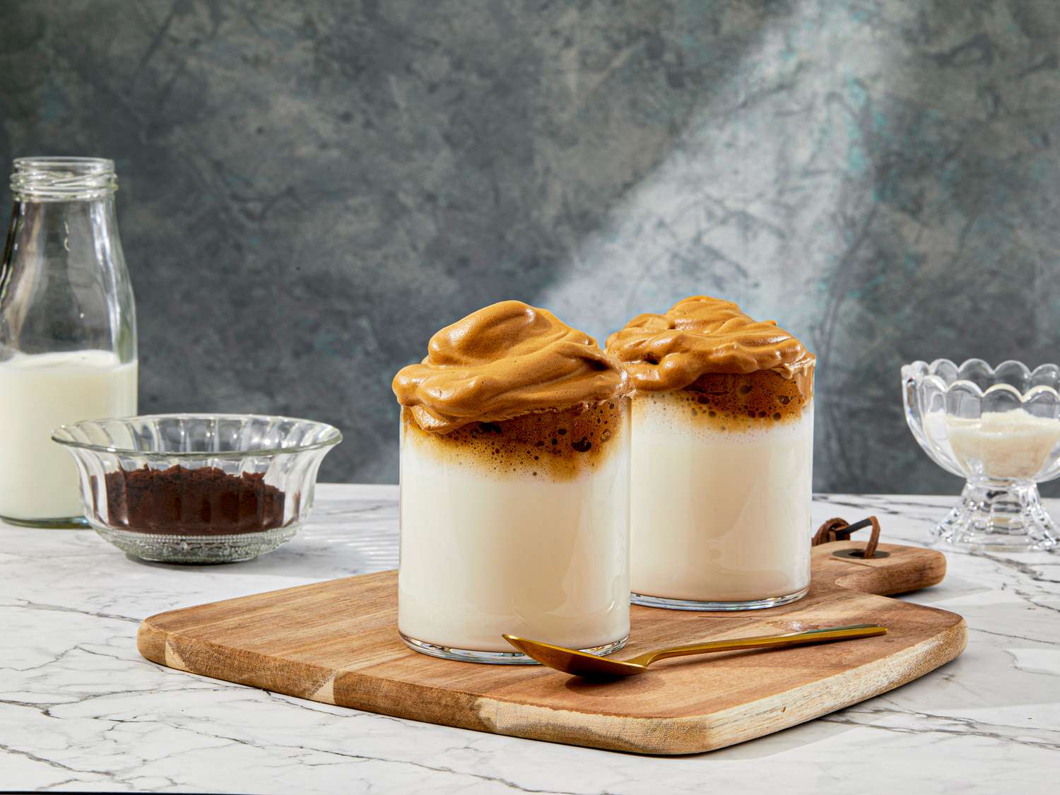 Two cups of Dalogna Coffee with ingredients surrounding it 