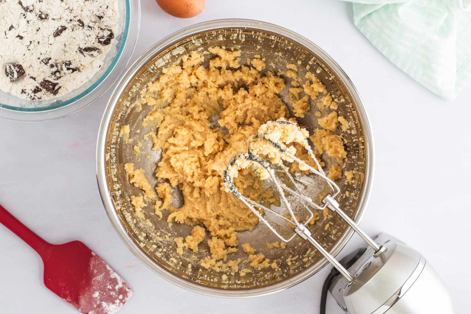 A stand mixer beside a bowl of cookie dough.