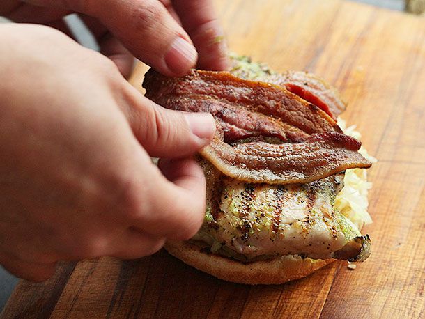 Author lays several pieces of grilled bacon on the chicken breast.