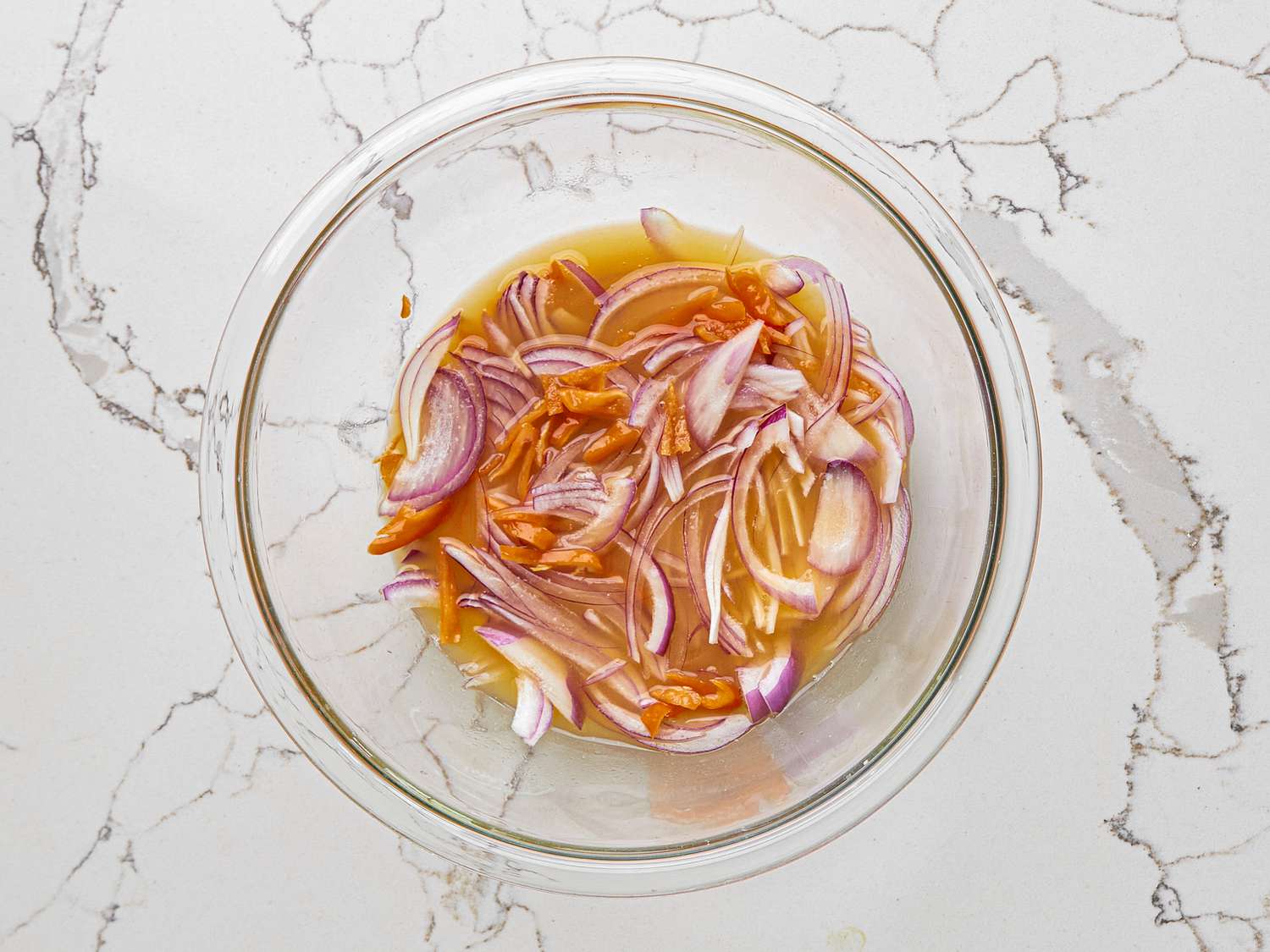 The onion and habanero for xnipec is pickled with citrus in a pyrex mixing bowl.