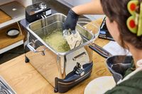 A person deep frying batter-coated food in the All-Clad Easy Clean Pro 3.5L Electric Deep Fryer