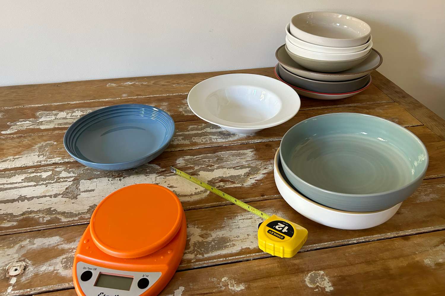 A collection of pasta bowls on a vintage table, with a tape measure in the foreground.. 