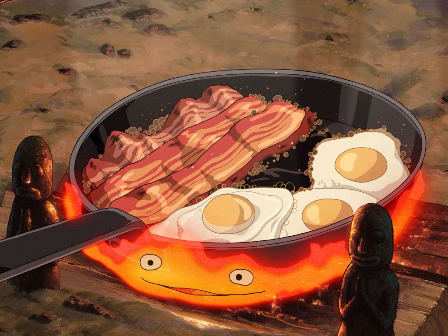 Bacon and eggs cook in a skillet over the flames of Calcifer (a fire demon).