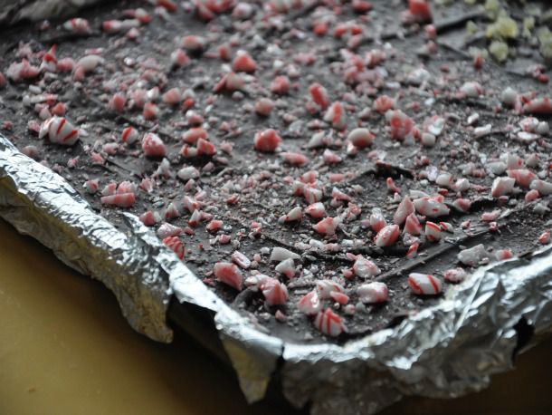 A foil-lined tray filled with peppermint bark that hasn't yet been sliced.