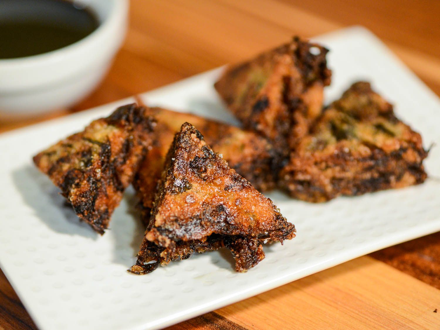 Plated triangles of crispy Thai fried rice cakes served with a side of dark soy dipping sauce.
