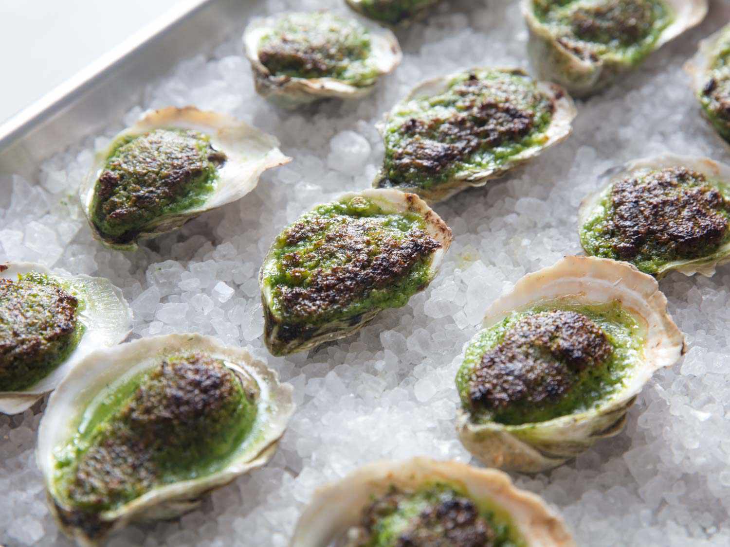 A baking sheet of Oysters Rockefeller resting on a layer of rock salt