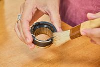 A person brushes a part from the OXO Brew Conical Burr Coffee Grinder