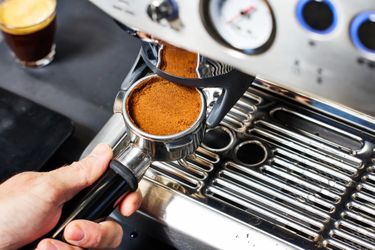 A person adjusting the portafilter onto the Breville Barista Express Impress