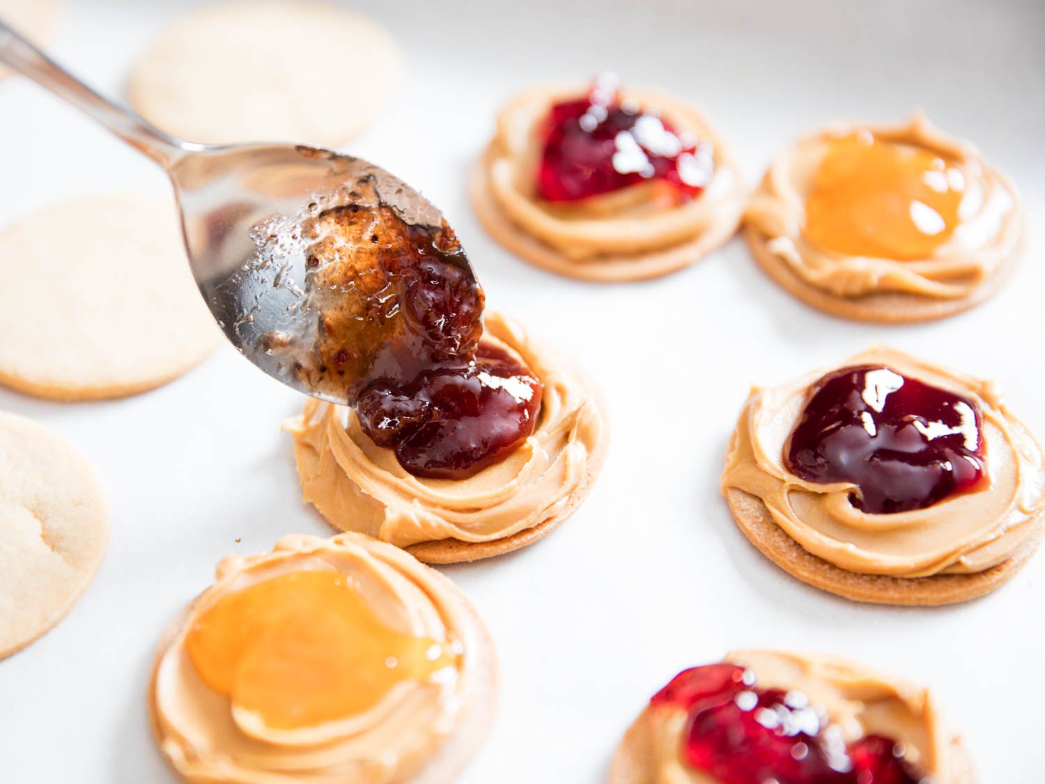 Closeup of cookies being filled with peanut butter and jelly.