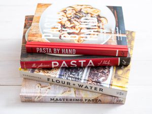 A stack of four cookbooks about pasta. 