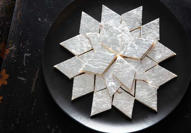 Overhead view of kaju katli, artfully arranged on a black plate.