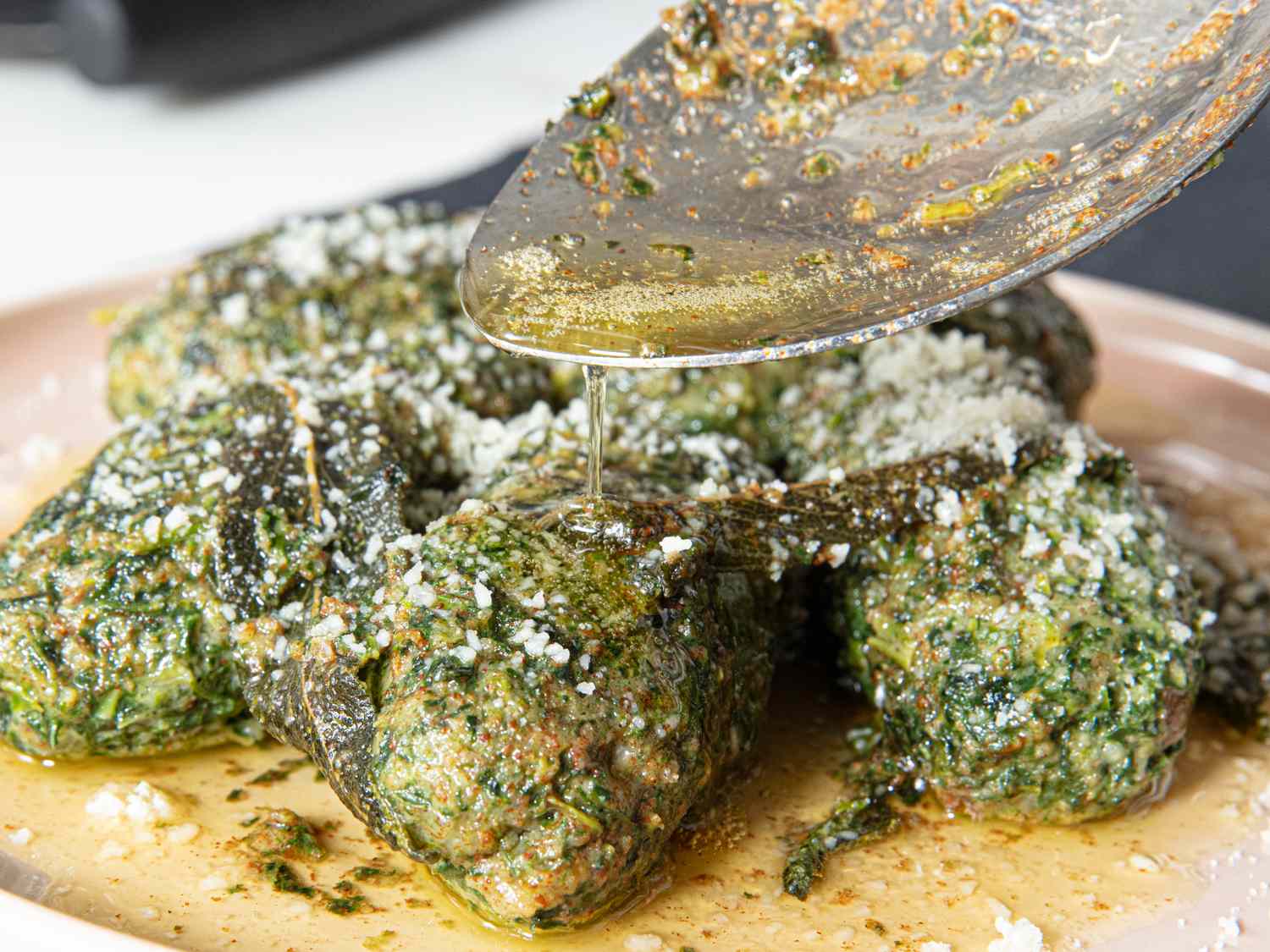 A dish with spinach dumplings or similar food drizzled with sauce and garnished with cheese