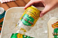 a hand pulling out a can of Sierra Nevada trail pass golden out of a bucket of ice