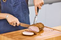 A person slices meat with the Wüsthof Classic Carving Set