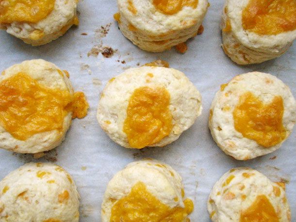 Overhead view of cheese buns on a parchment-lined baking sheet, fresh from the oven.