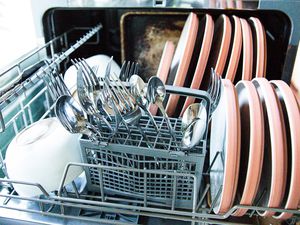 A countertop dishwasher filled with dishes and silverware.