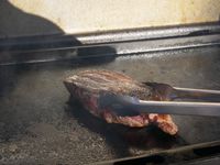flipping a piece of steak on the griddle
