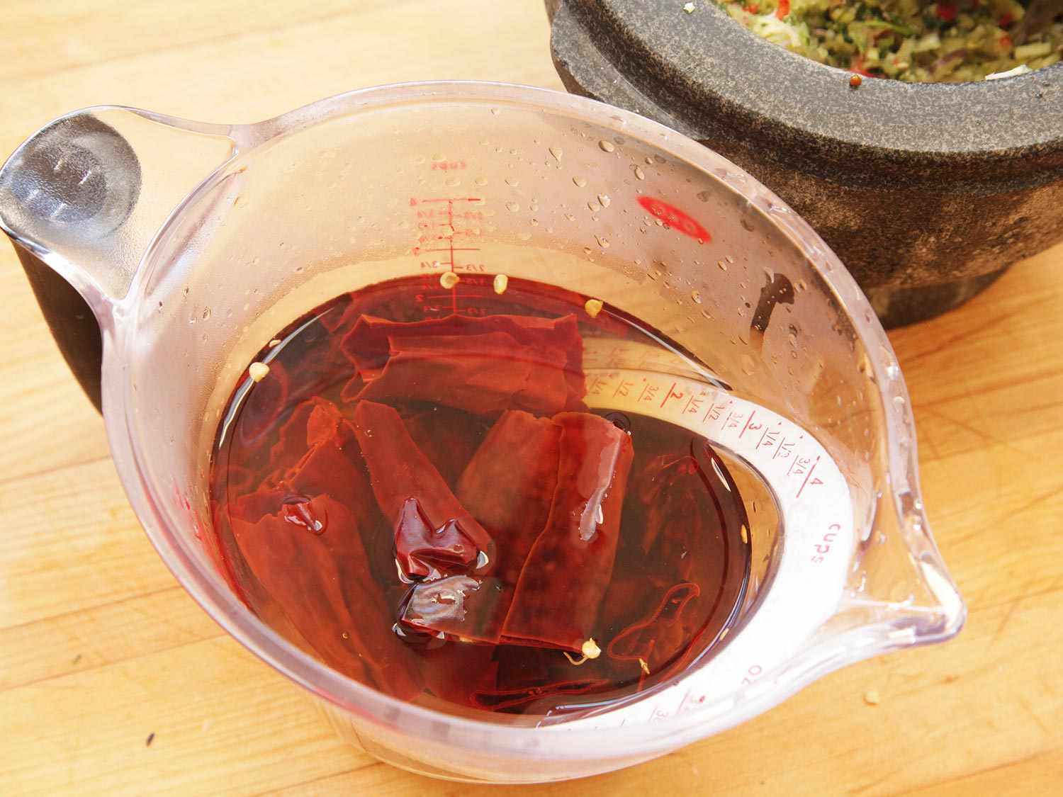 Rehydrating red chiles in a measuring cup of hot water.