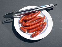 the oxo tongs resting on a plate of grilled hot dogs