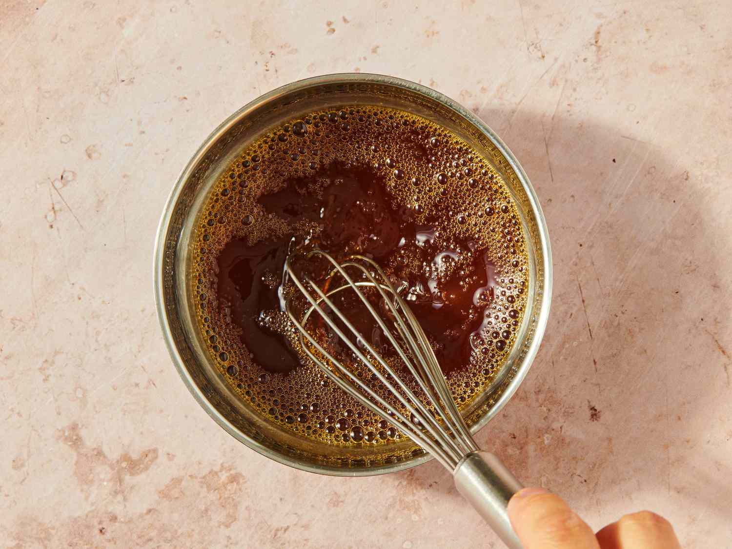 A bowl of sauce being whisked by hand preparing a dish