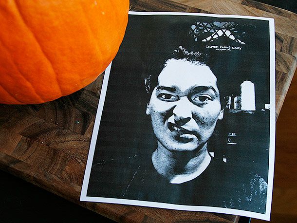 A printed black-and-white photo of a sneering woman's face, next to a pumpkin for carving