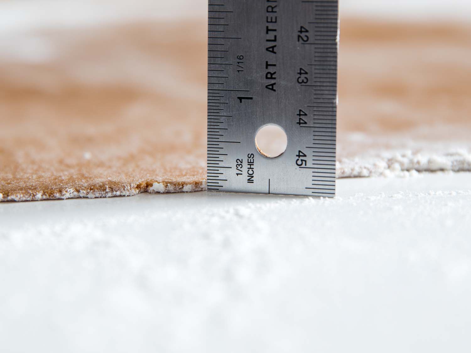 Measuring gingerbread cookie dough thickness with a ruler. It reads 1/8 inch.
