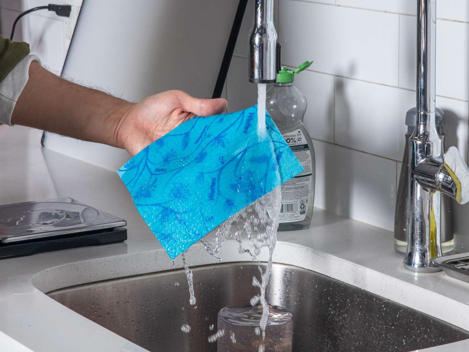 A Swedish dishcloth underneath a running faucet