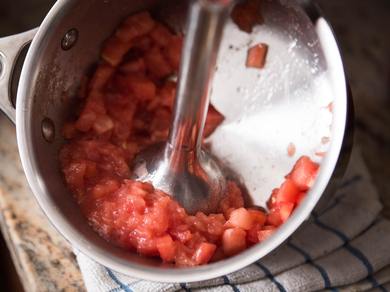 An immersion blender is used to purée the drained tomato flesh.