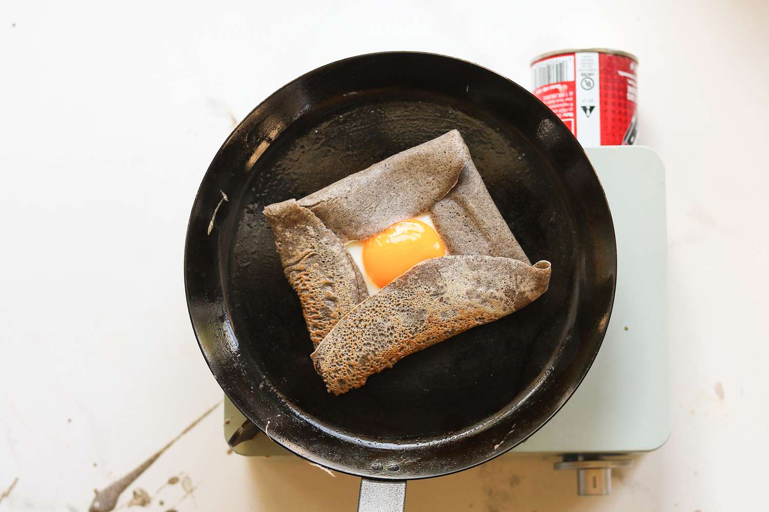 A buckwheat crepe with an egg in the center on a carbon steel crepe pan.