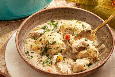 Chicken dumpling soup in a bowl with a spoon garnished with parsley