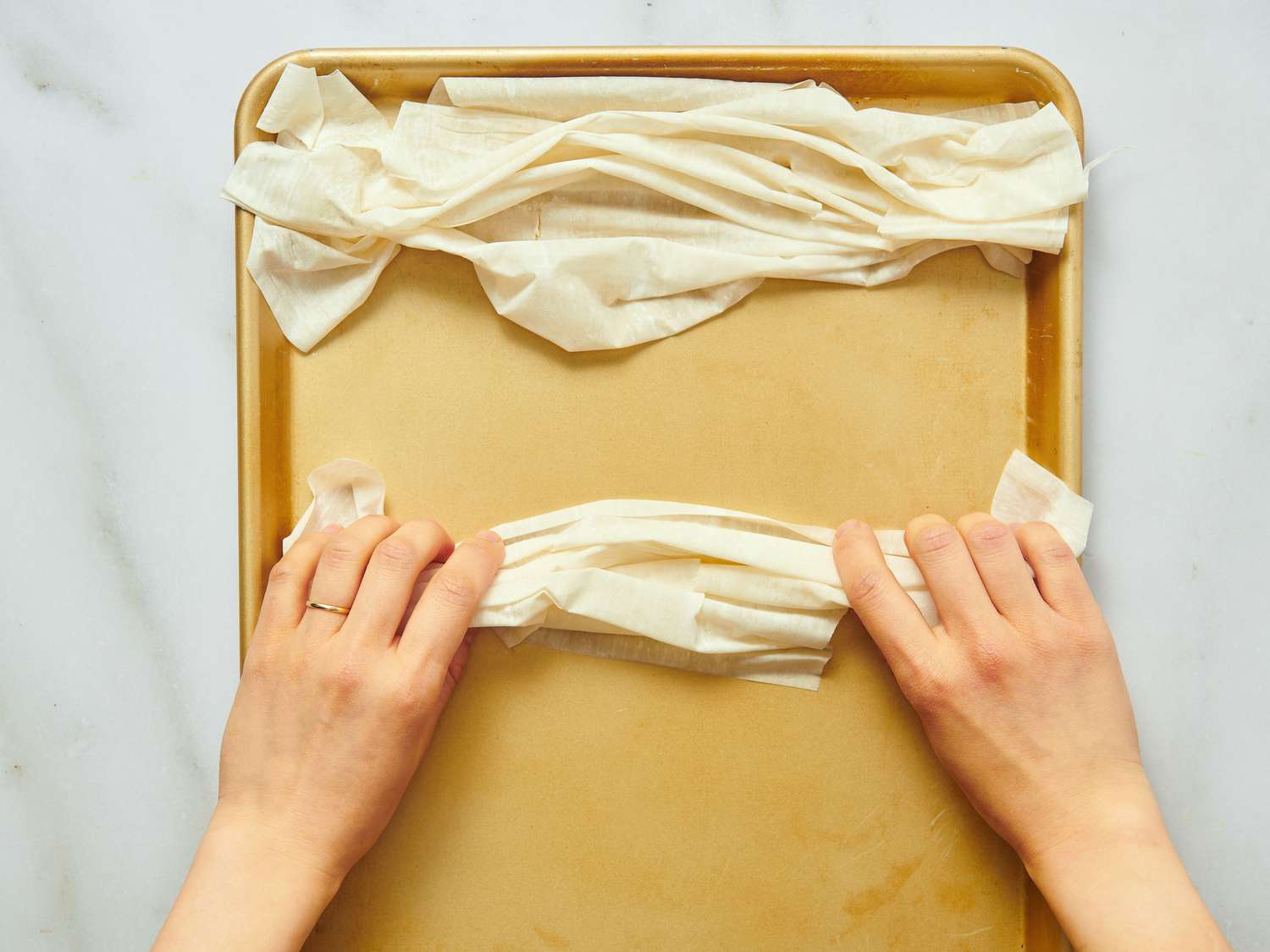 A person's hands shaping dough on a baking sheet