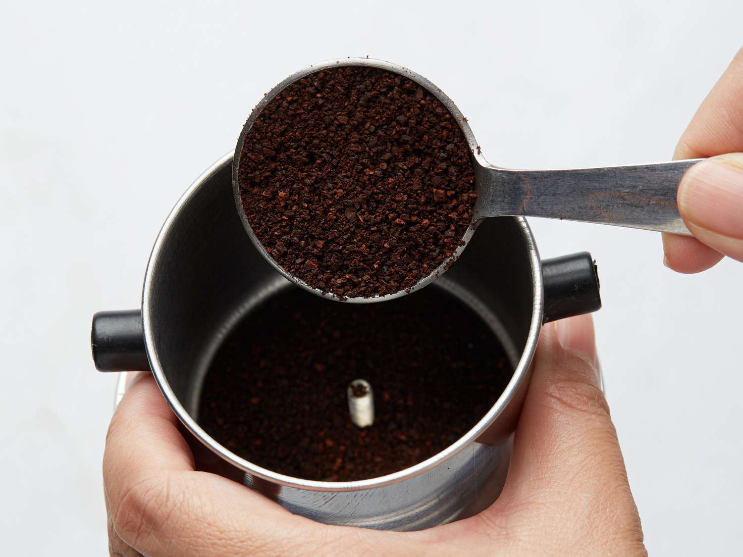 Placing coffee grounds in a phin filter.