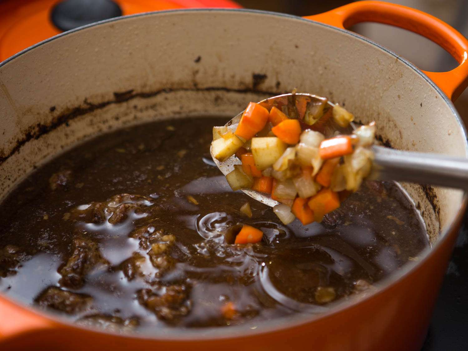 Adding sauteed vegetables to simmering beef stew