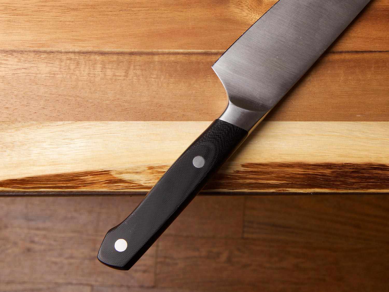 The handle of a chef's knife hanging over the edge of a counter