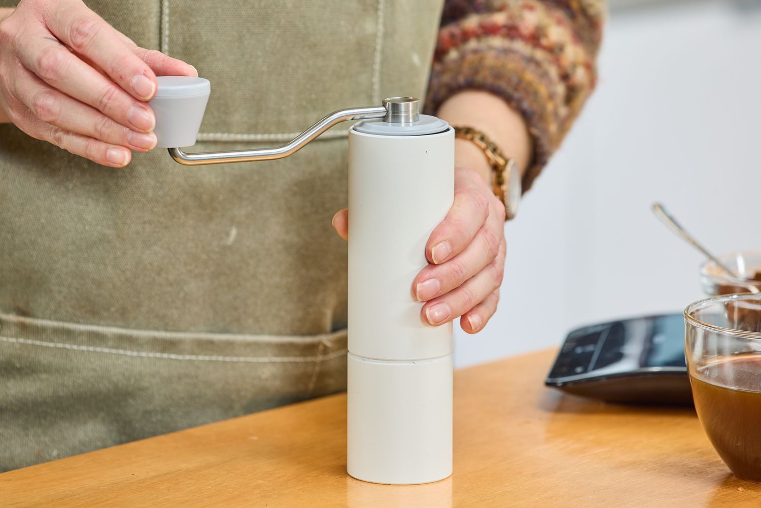 A person turns the crank on the top of the Timemore C2 Max Manual Grinder