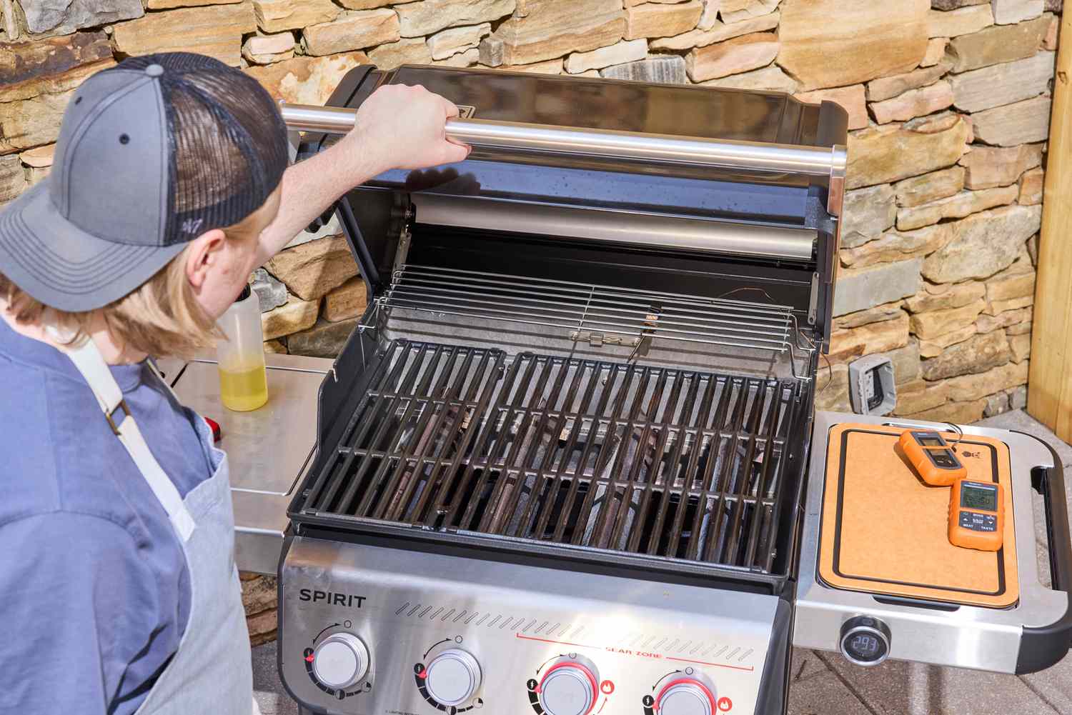 A hand opening the hood of the Weber Spirit EP-435 Gas Grill