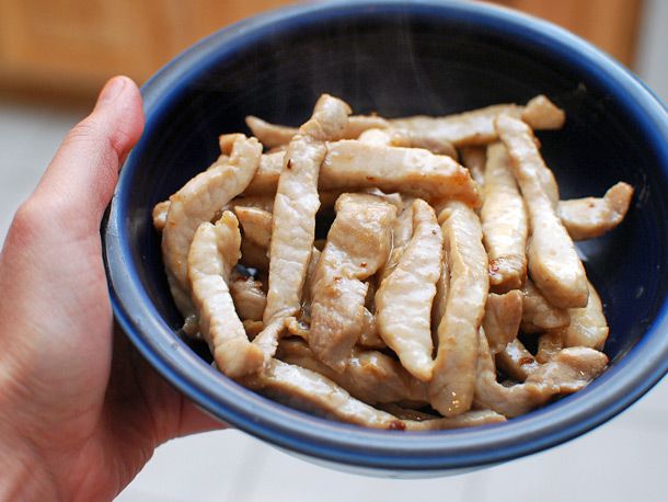 Setting aside cooked pork loin strips in a bowl