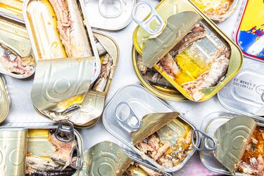 Opened sardine cans scattered on a surface showing their contents of fish