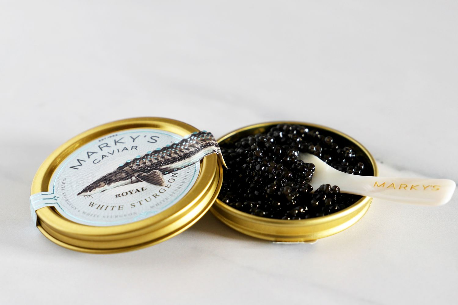 A tin of royal white sturgeon caviar with a mother-of-pearl spoon set inside