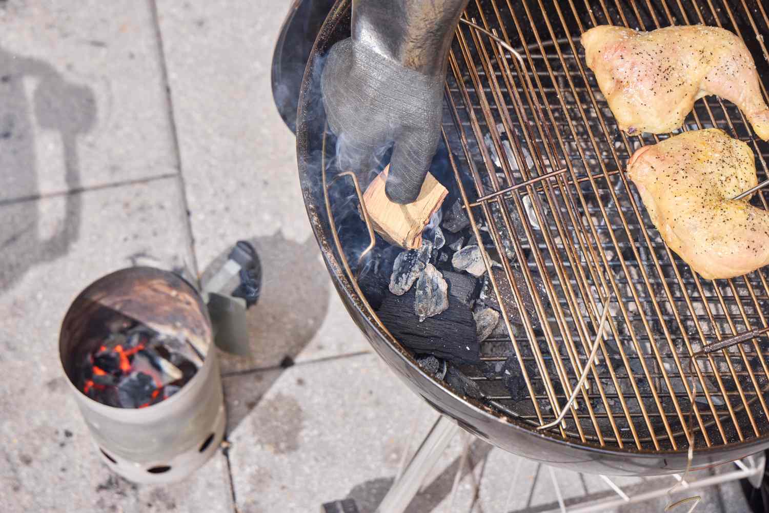 A hand touching inside the great of the Weber Original Kettle Premium 22-Inch Charcoal Grill as it cooks chicken