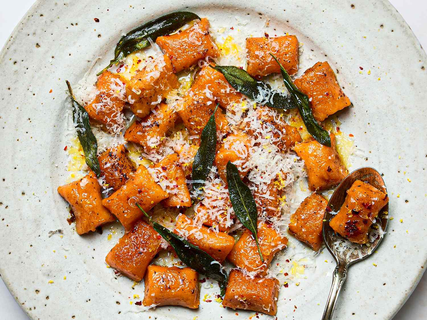 Plate of sweet potato gnocchi topped with grated cheese crispy sage and brown butter
