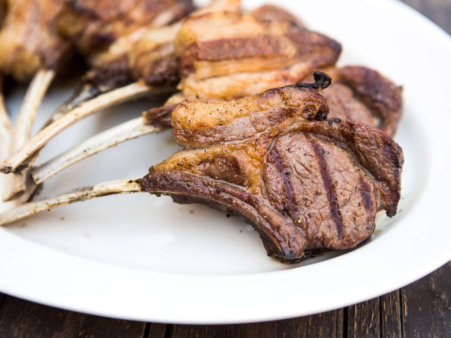 Perfectly grilled lamb chops shingled on a plate, edges slightly charred.