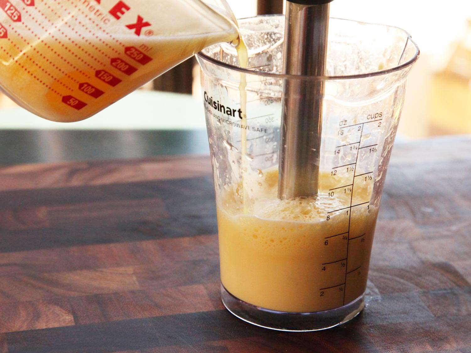 Pouring hot butter into a measuring cup with an immersion blender 