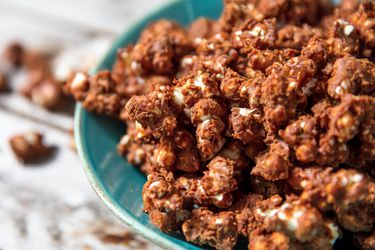 Closeup of a blue bowl overflowing with crispy chocolate popcorn.